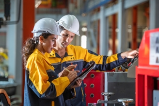 A man and a young girl wearing construction gear whilst working.